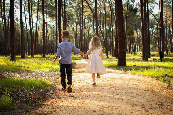 Two children running on a path, a young boy and girl dressed in clothing provided by Liberty and Whimsy Boutique